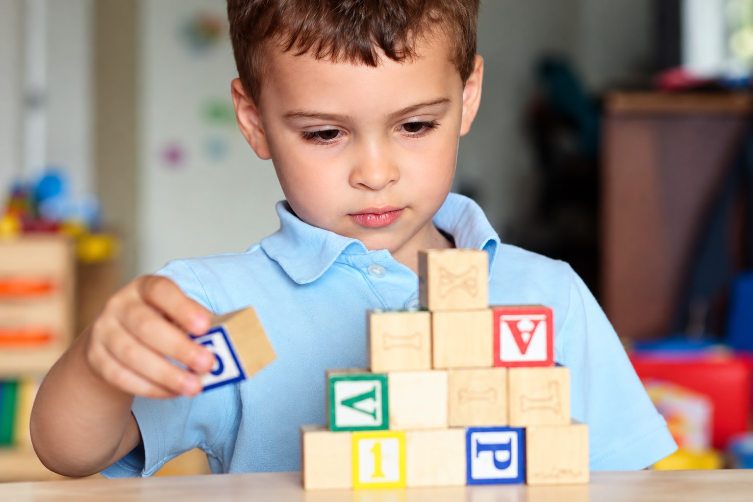 A child concentrating on arranging wooden learning blocks.