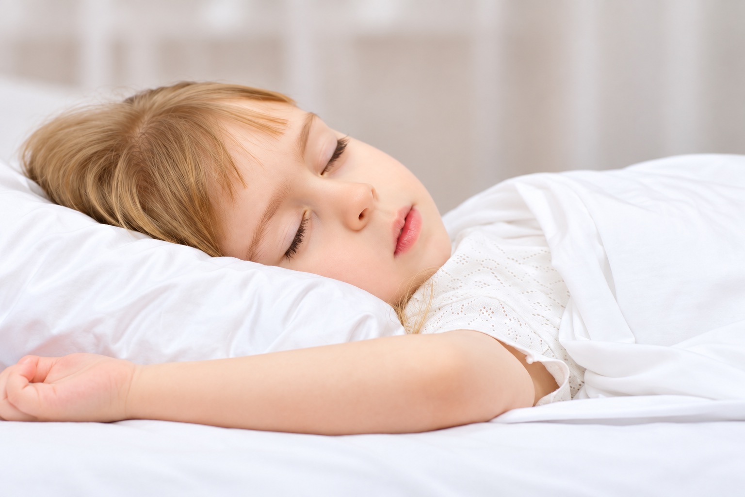 A child sleeping on a white pillow under a blanket.